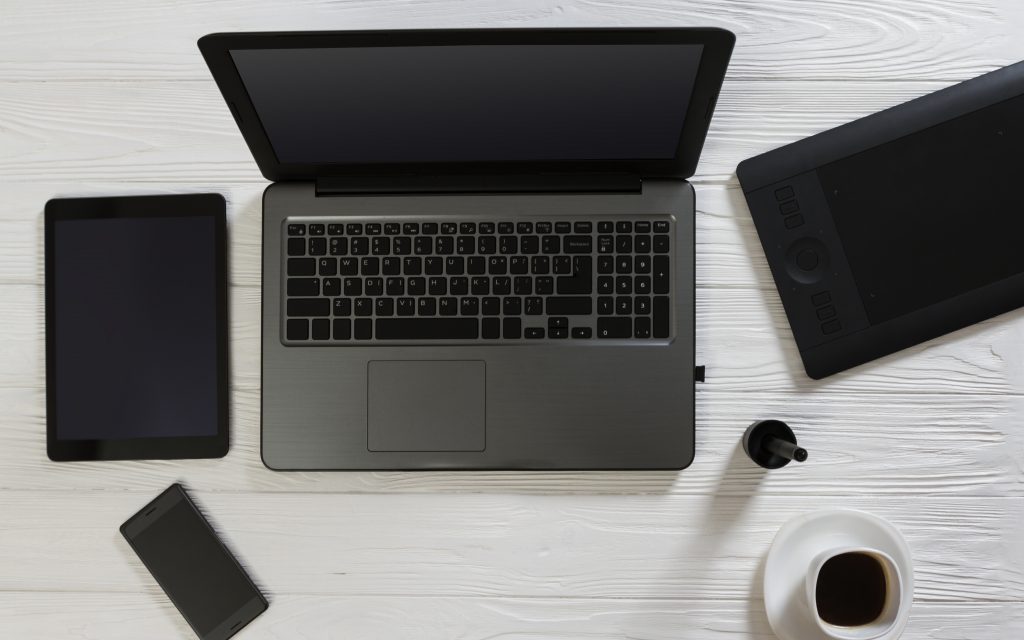 Desktop items top view on wooden background - Laptop and tablet with a cup of coffee on white desktop